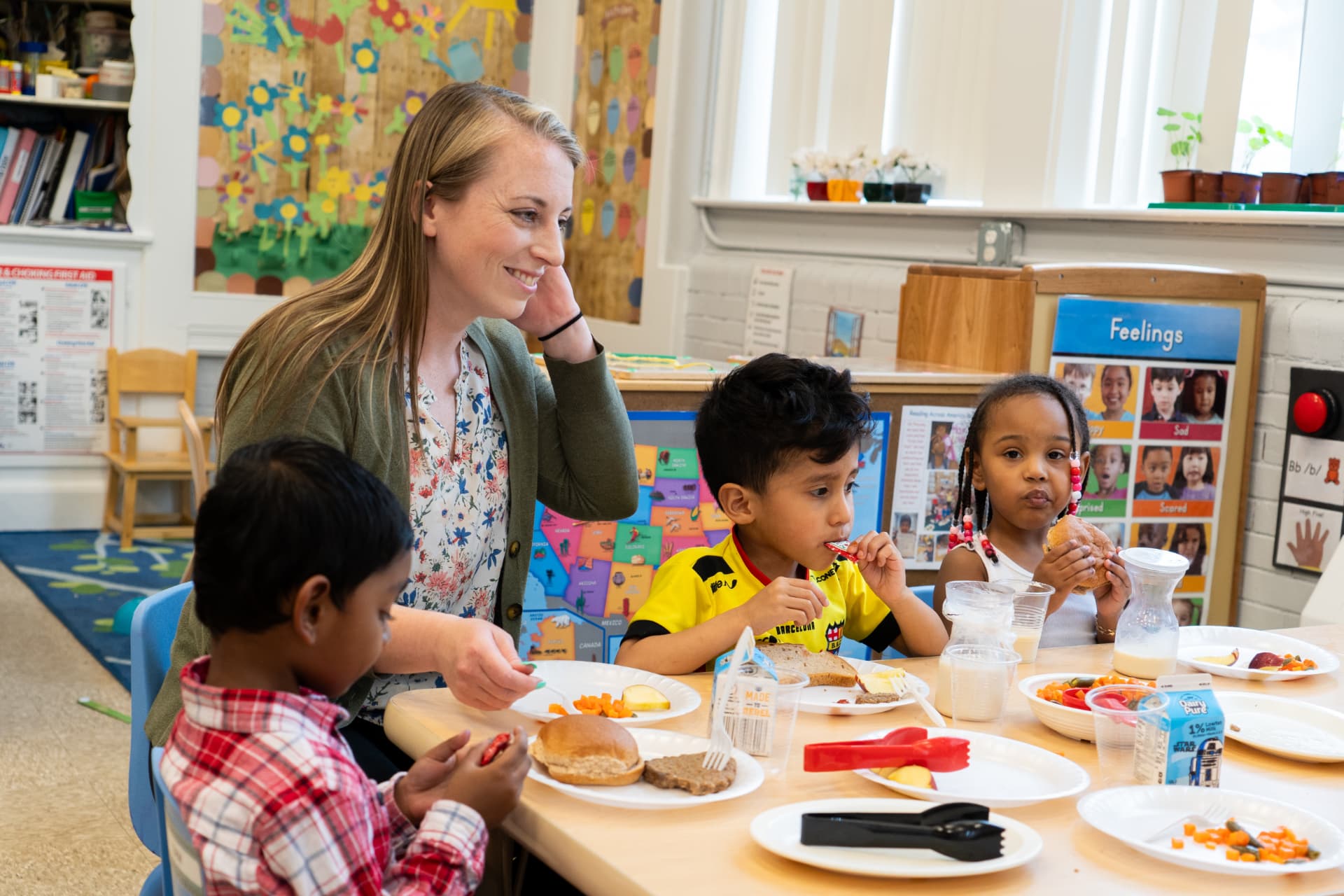 A TEAM educator sharing lunch with children in a bright classroom